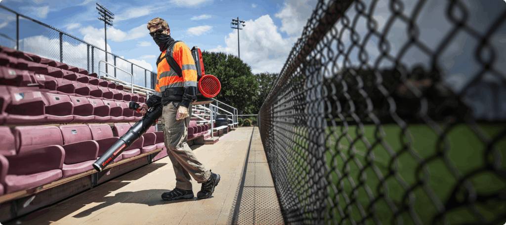 Groundsman in hi-vis clearing a walkway with a Kress KC500 60 V backpack blower