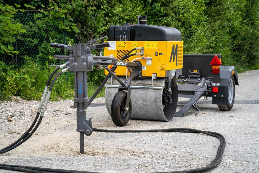 Mecalac MBR71 pedestrian roller on site with a hydraulic breaker connected to its take-off