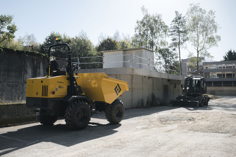 Mecalac TA9H site dumper parked in a yard beside an excavator