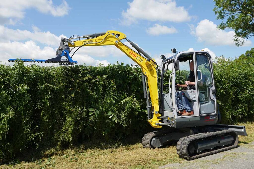 Slanetrac HC150 finger-bar hedge cutter on a mini digger trimming the top of a hedge
