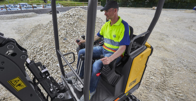 Operator at the controls of a Volvo EC15E canopy compact excavator