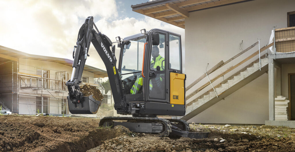 Volvo EC18E compact excavator digging beside a new house